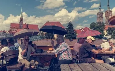 emeryci pod parasolami płyną na łodzi